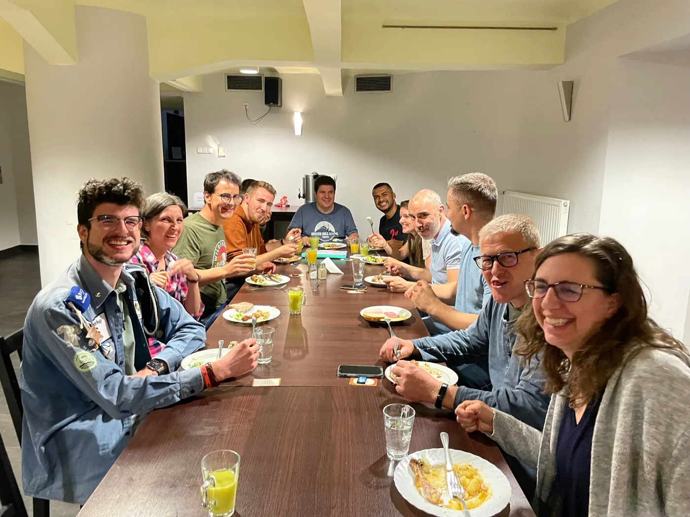 Grosse Runde beim Essen am langen Tisch, ausgelassene Stimmung