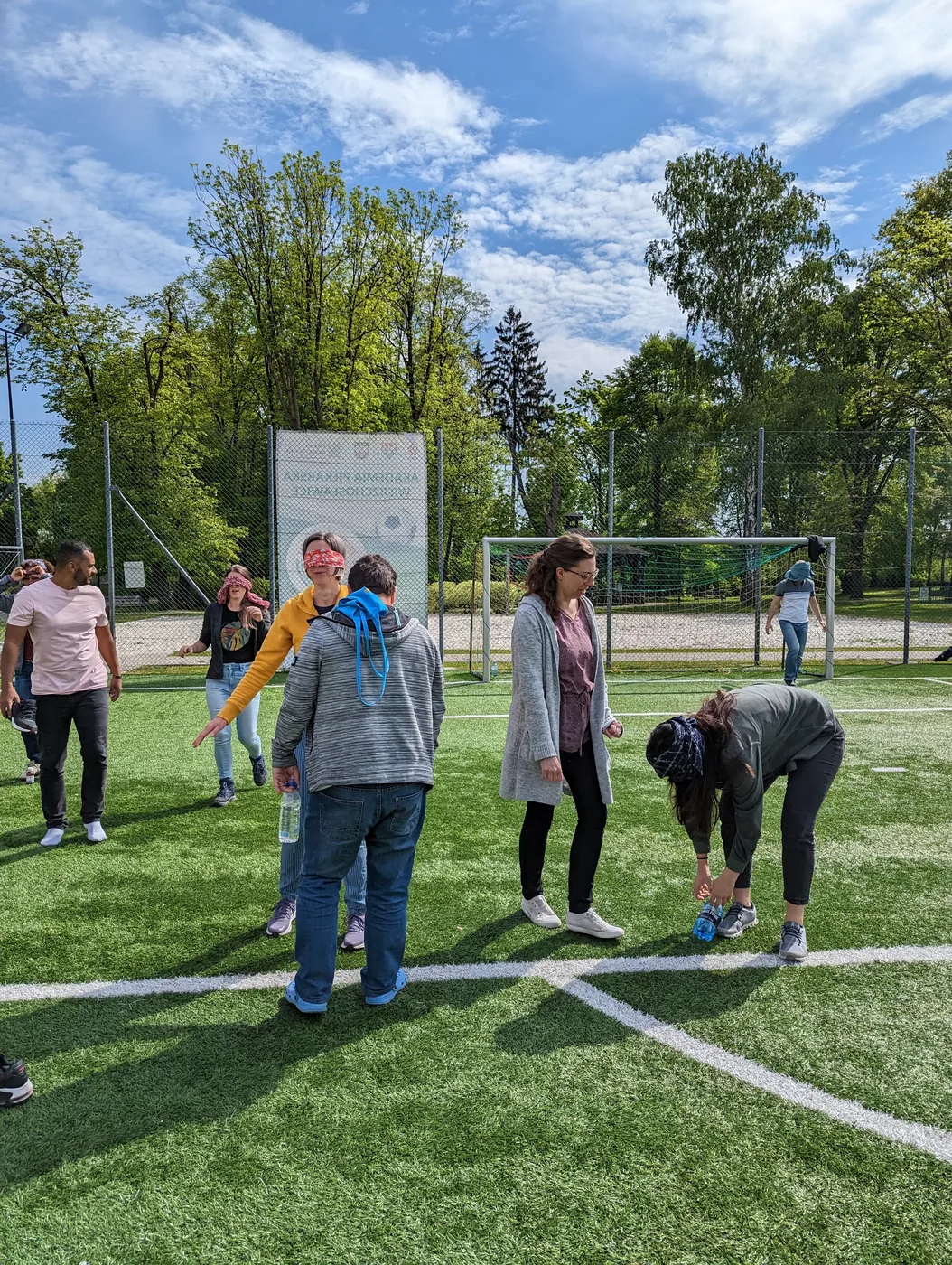 Gruppenspiel mit Augenbinden auf dem Sportplatz, viel Interaktion