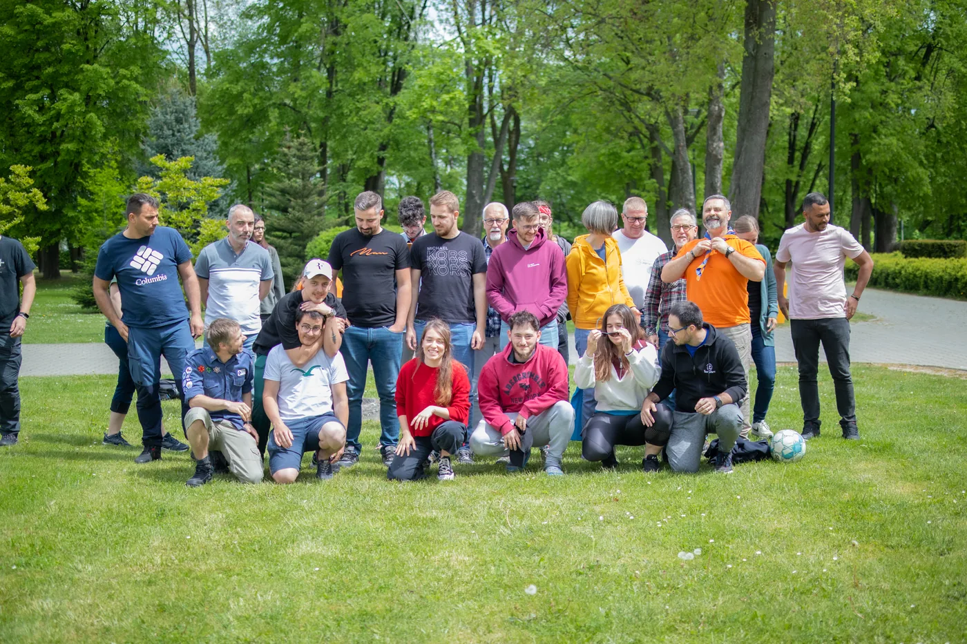 Lockeres Gruppenfoto der ganzen Runde auf der Wiese im Park, Fussball am Rand