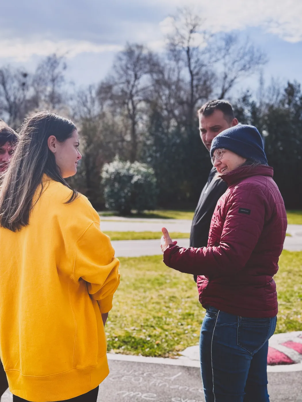 Lebendiges Gruppengespräch draussen, Frau in bordeauxroter Jacke lacht
