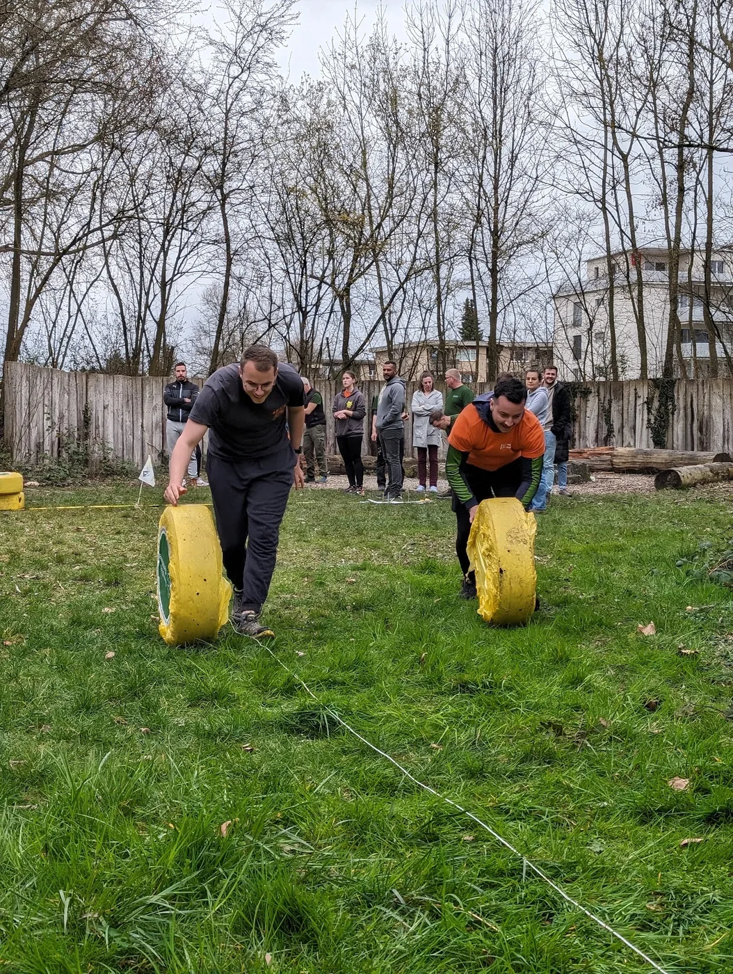 Zwei Teilnehmer im Wettrennen mit Käserollen, Zuschauer im Hintergrund