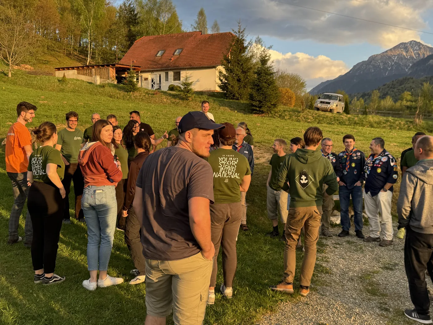 Gruppe steht in der Abendsonne auf der Wiese zusammen, Youngstars-Shirts und Abzeichen sichtbar