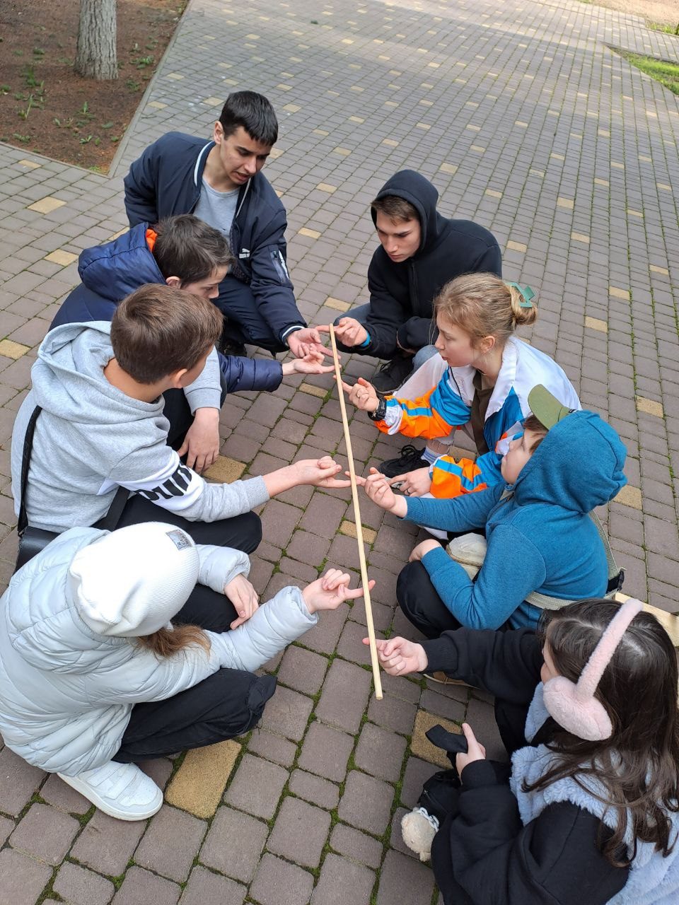 Im Kreis mit dem Stab: Ein Kooperationsspiel auf dem Kirchengelände.